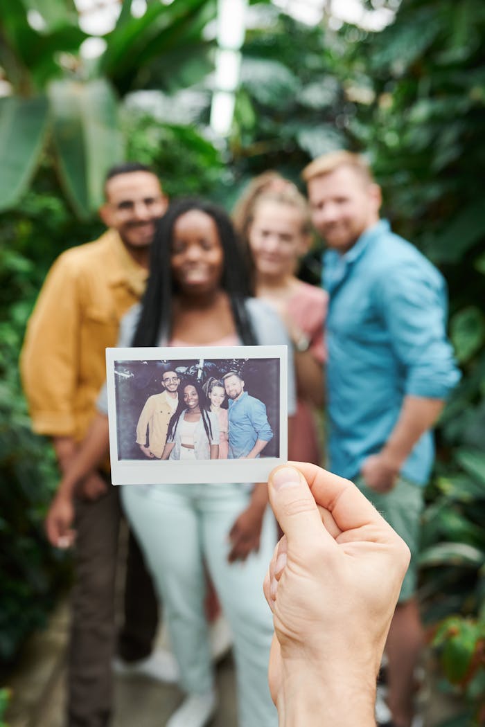Group of friends holding a Polaroid photo in a lush tropical environment, celebrating friendship.